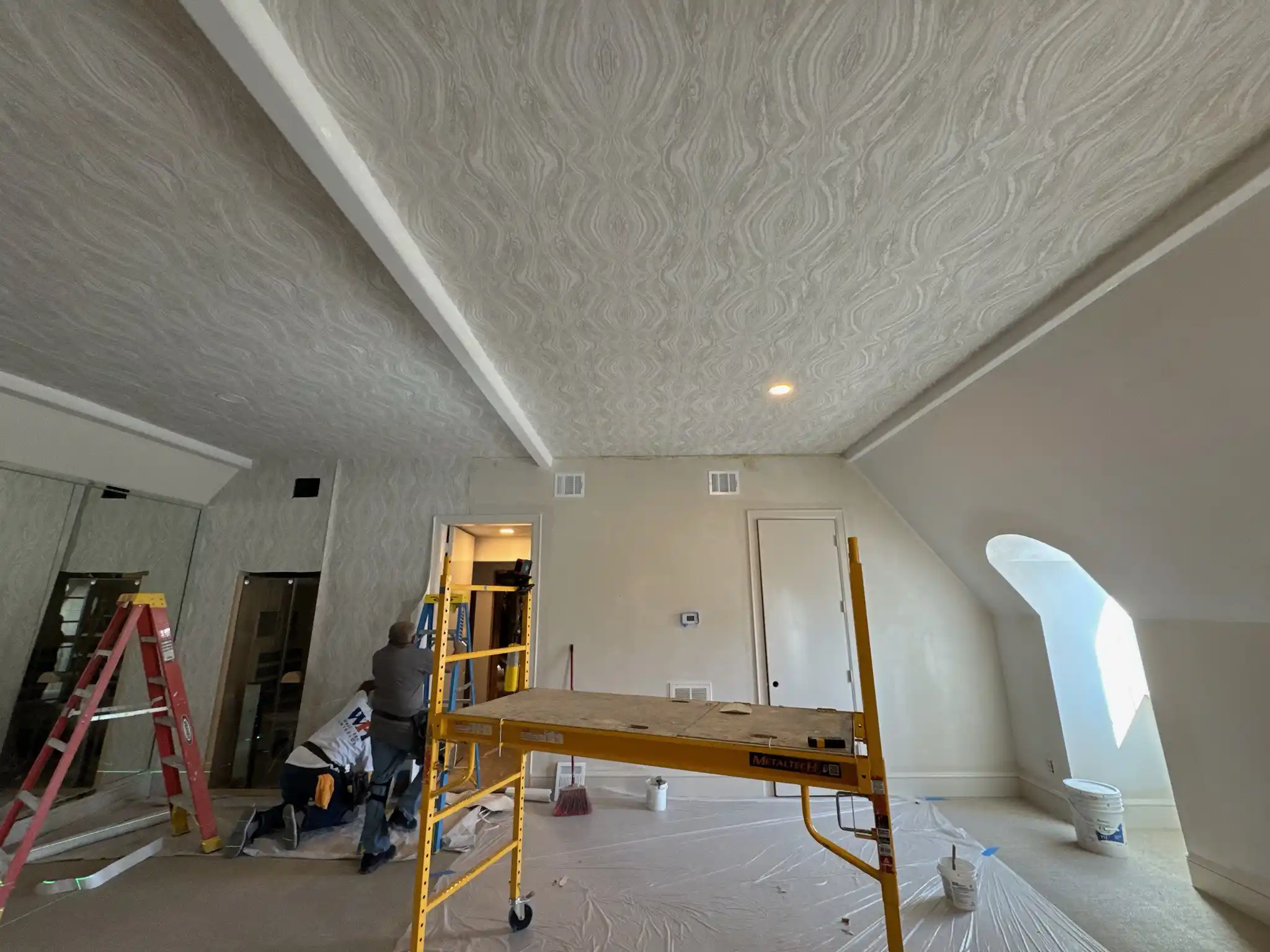 Sebastian Kelly preparing a wall for wallpaper installation